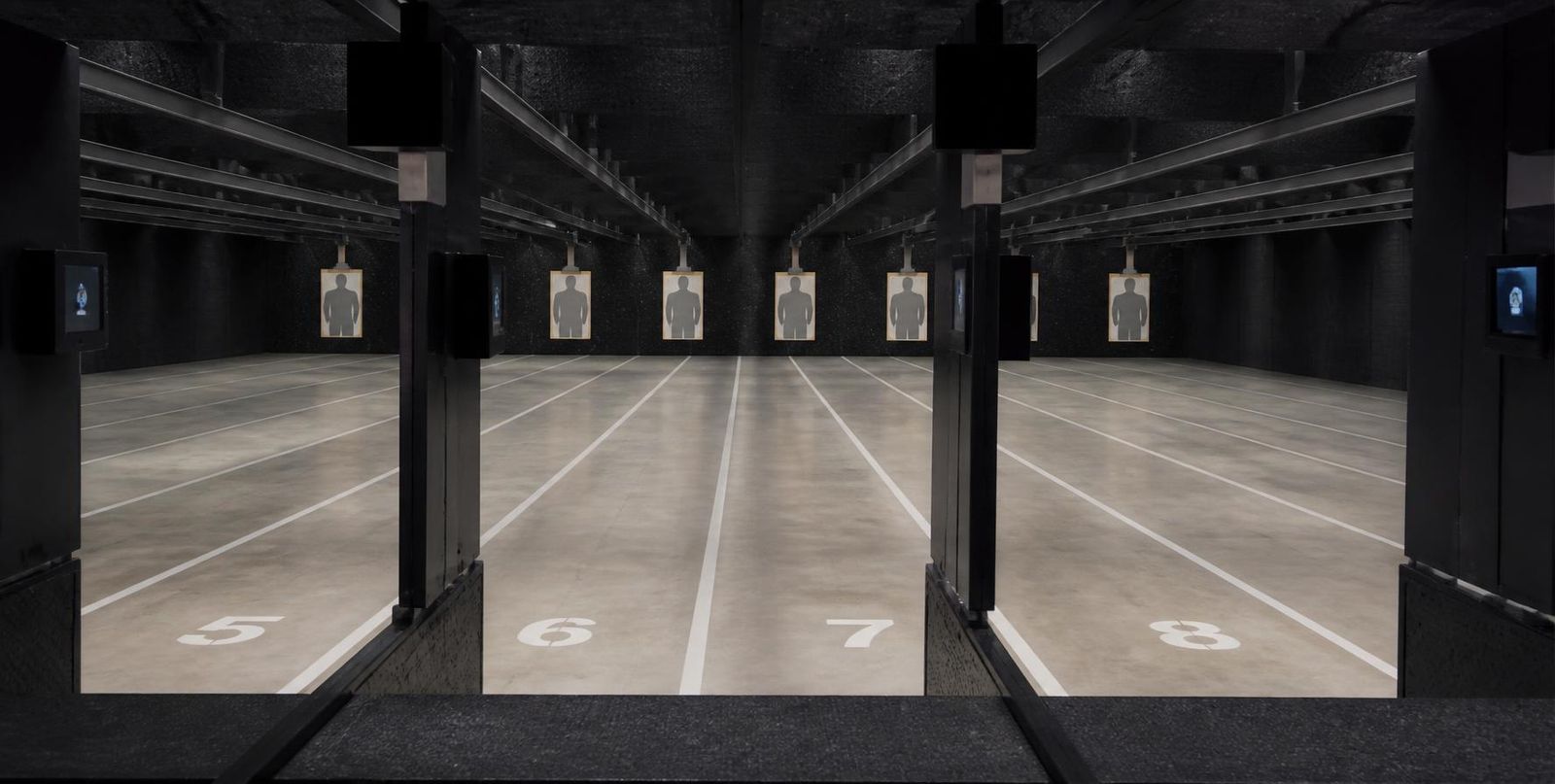 Numbered lanes at an indoor shooting range, targets downrange